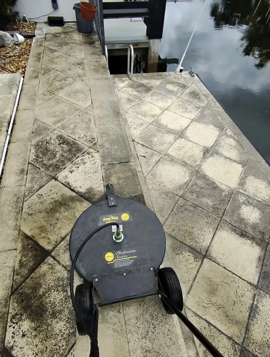 Professional surface cleaner cleaning a dirty concrete dock, with the clean section visible beside it